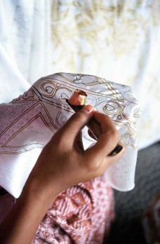 Artist uses a canting tool to apply the hot wax